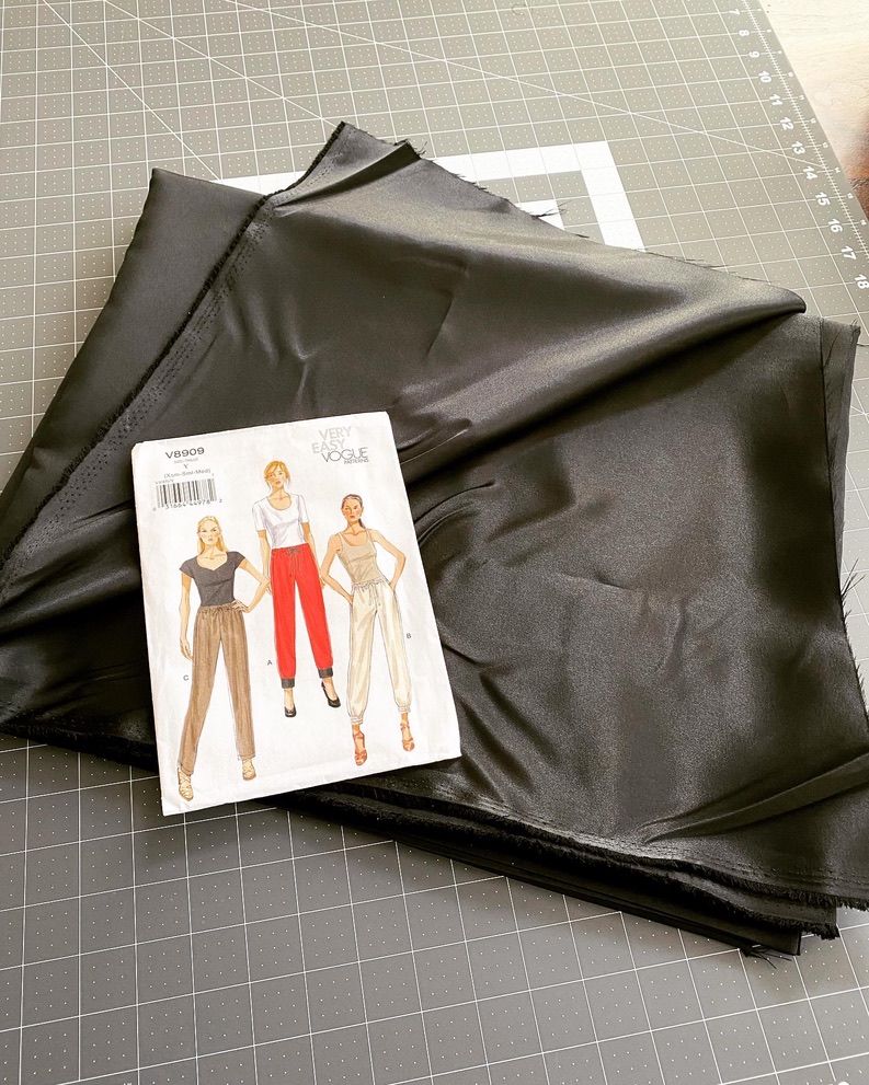 Black fabric and a Vogue sewing pattern on a cutting mat